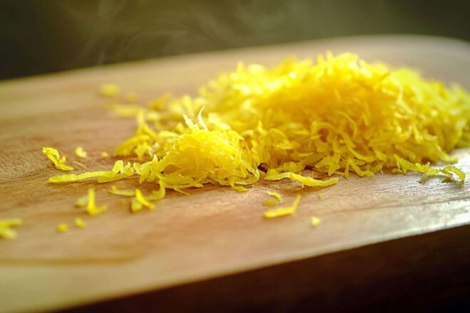 Zeste de citron vibrant sur une planche en bois, mettant en valeur sa couleur jaune éclatante.