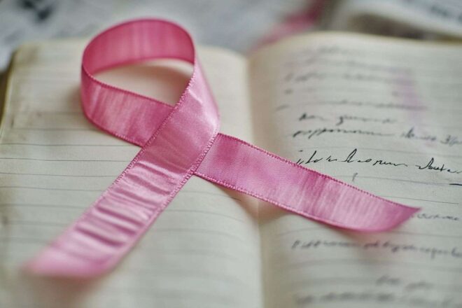 Gros plan d'un ruban rose sur un journal avec des citations motivantes sur la santé et le bien-être.