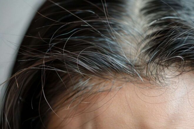 Gros plan sur le front d une femme avec des mèches de cheveux fins dans la brise