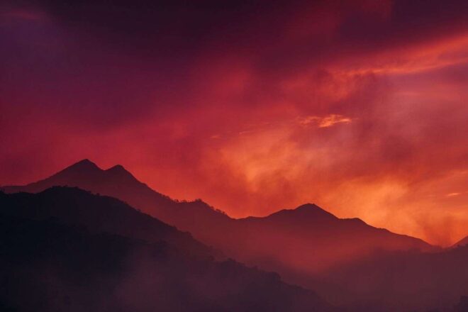 Silhouettes de montagnes lointaines sous un ciel rouge dramatique