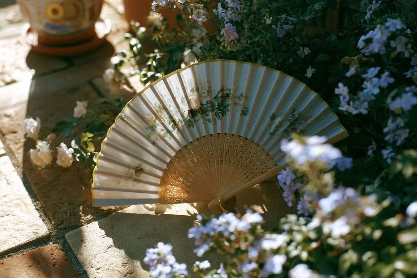 Image d’un éventail chic sur une terrasse lumineuse parmi des plantes fleuries