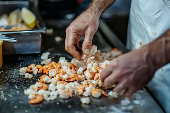 Vue aérienne de la préparation des crevettes avec des épluchures éparses, créant une ambiance de cuisine animée.