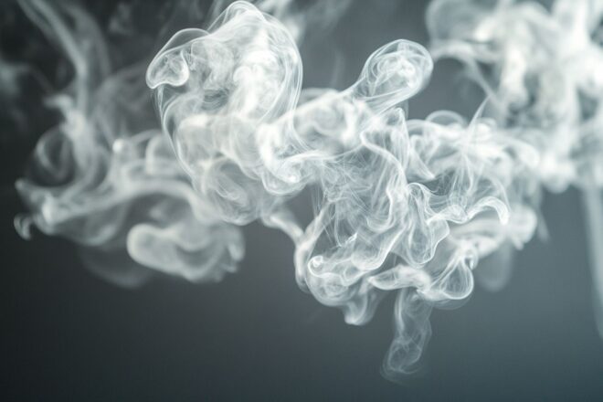 Gros plan de vapeur tourbillonnante dans l'air au-dessus d'un dispositif électronique, capturé en lumière naturelle douce.