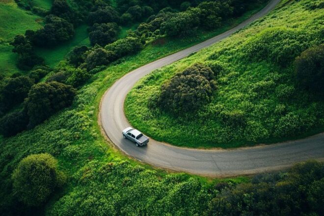Vue plongeante d un pick up sur une route sinueuse entourée de collines vertes