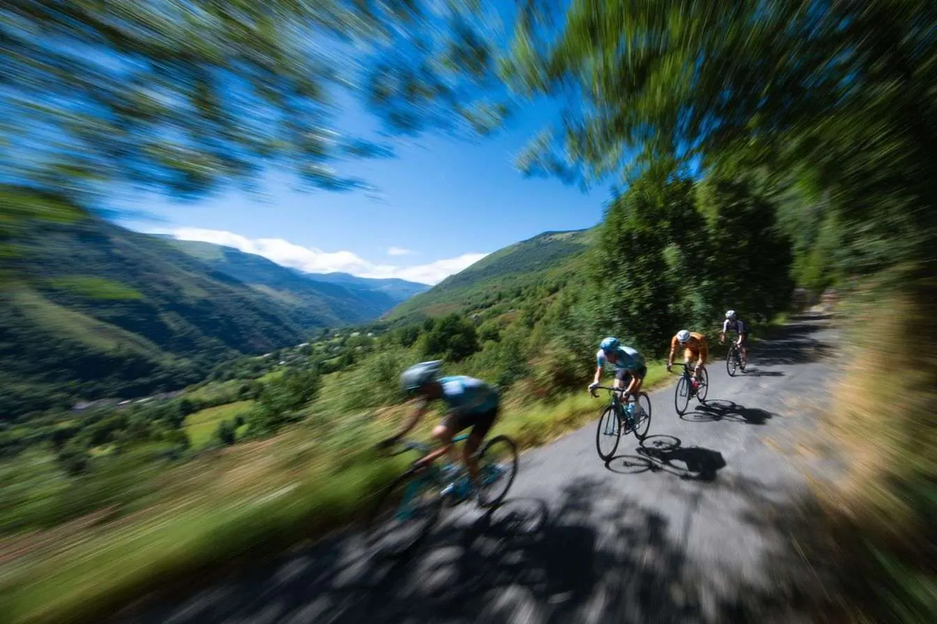 Course de cyclistes sur une route montagnarde bordée de verdure et ciel dégagé