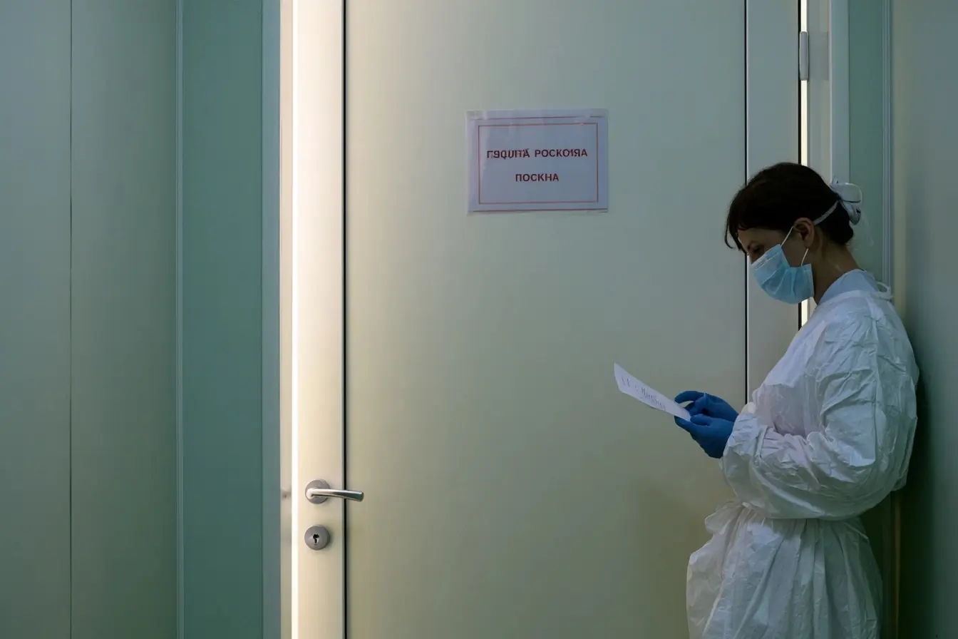 Soignant masqué devant une porte d’isolement